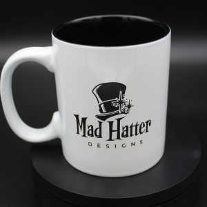 White mug with black Mad Hatter logo engraved on the front
